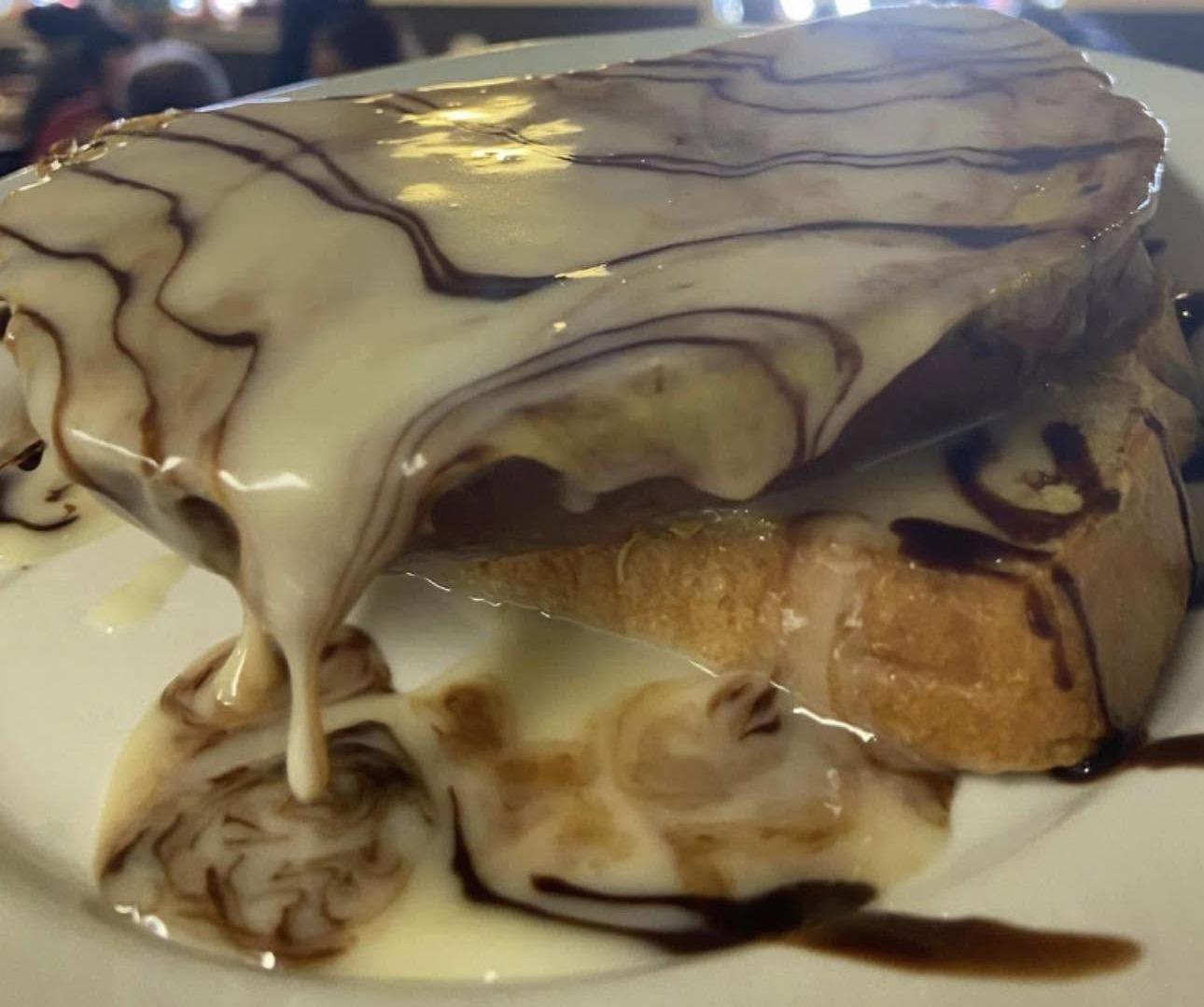 A dessert under white and dark chocolate drizzle on a white plate
